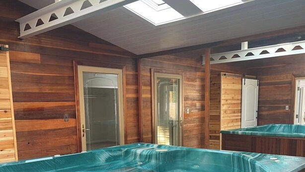 A hot tub in a wooden room with skylights and doors. - Spacious Home with Heated Swimming Pool + Hot Tub + Event Room + SLEEPS 23 (Owensboro)