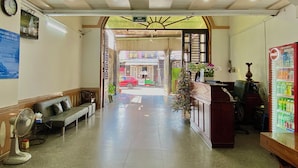 Um saguão de hotel com um balcão de recepção, um relógio, um sofá e uma geladeira Coca-Cola.