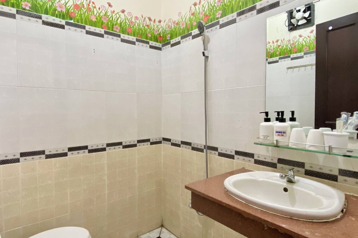 A bathroom with a toilet, a sink, and a shower. There are toiletries on the sink counter.