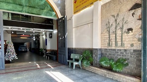 Entrada de hotel com uma grande placa, uma árvore de Natal e um mural na parede.