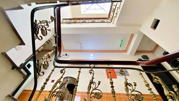 Uma escadaria com grades de metal ornamentadas e um guarda-corpo de vidro.