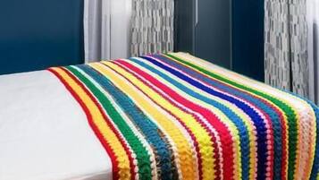 Ein Schlafzimmer mit Bett, blauen Wänden und weißen Vorhängen.