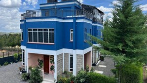 A two-story building with a blue and white exterior, a balcony on the upper floor, and a small front porch area. - The Fairway Residence - Tanyai (Tanyai)