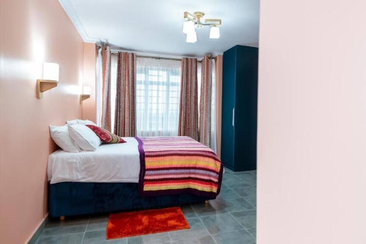 Une chambre à coucher avec un lit, un tapis rouge et une fenêtre avec des rideaux.