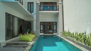 Ein modernes Gebäude mit Pool, großen Fenstern und einem Balkon mit Gartenmöbeln.