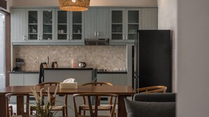 Eine moderne Küche mit hellblauen Schränken, einem schwarzen Kühlschrank und einem Essbereich mit Holztischen und einer Tischplatte.