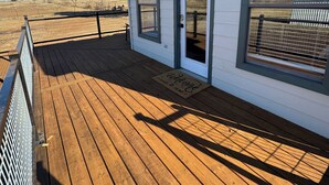 A wooden deck with a white building featuring a door and windows. - Cozy cottage with fresh baked goods (Colorado City)