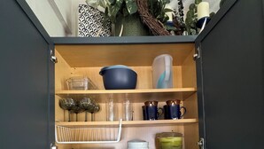 A kitchen with two stainless steel sinks, a striped towel, a bottle, and a shelf with dishes and glasses. - Cozy cottage with fresh baked goods (Colorado City)
