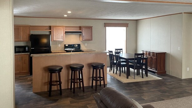 Una cocina moderna con una isla central, taburetes de bar y una zona de comedor con una mesa grande y sillas.