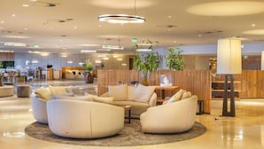 A modern lobby with a reception desk, seating area with sofas, and a large plant. - Oceanfront B2B (Rio de Janeiro)