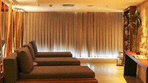 A modern lobby with a sofa, a reception desk, and a large window with vertical blinds. - Oceanfront B2B (Rio de Janeiro)