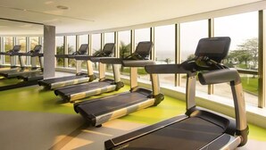 A row of treadmills in a gym with large windows and a green floor. - Oceanfront B2B (Rio de Janeiro)