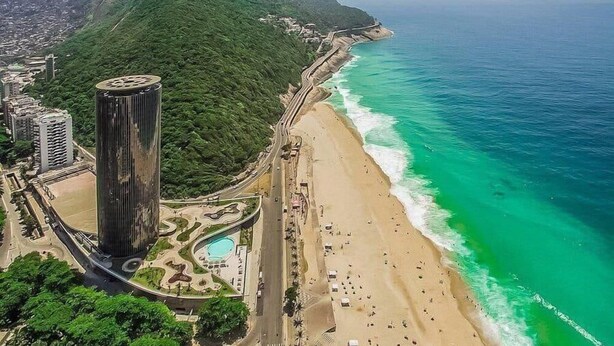 A coastal cityscape with a tall skyscraper, a beach, and a road leading to the beach. - Oceanfront B2B (Rio de Janeiro)