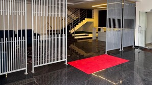 Eine moderne Hotellobby mit einem polierten schwarzen Boden, einem roten Teppich und einer Treppe, die in eine obere Etage führt.