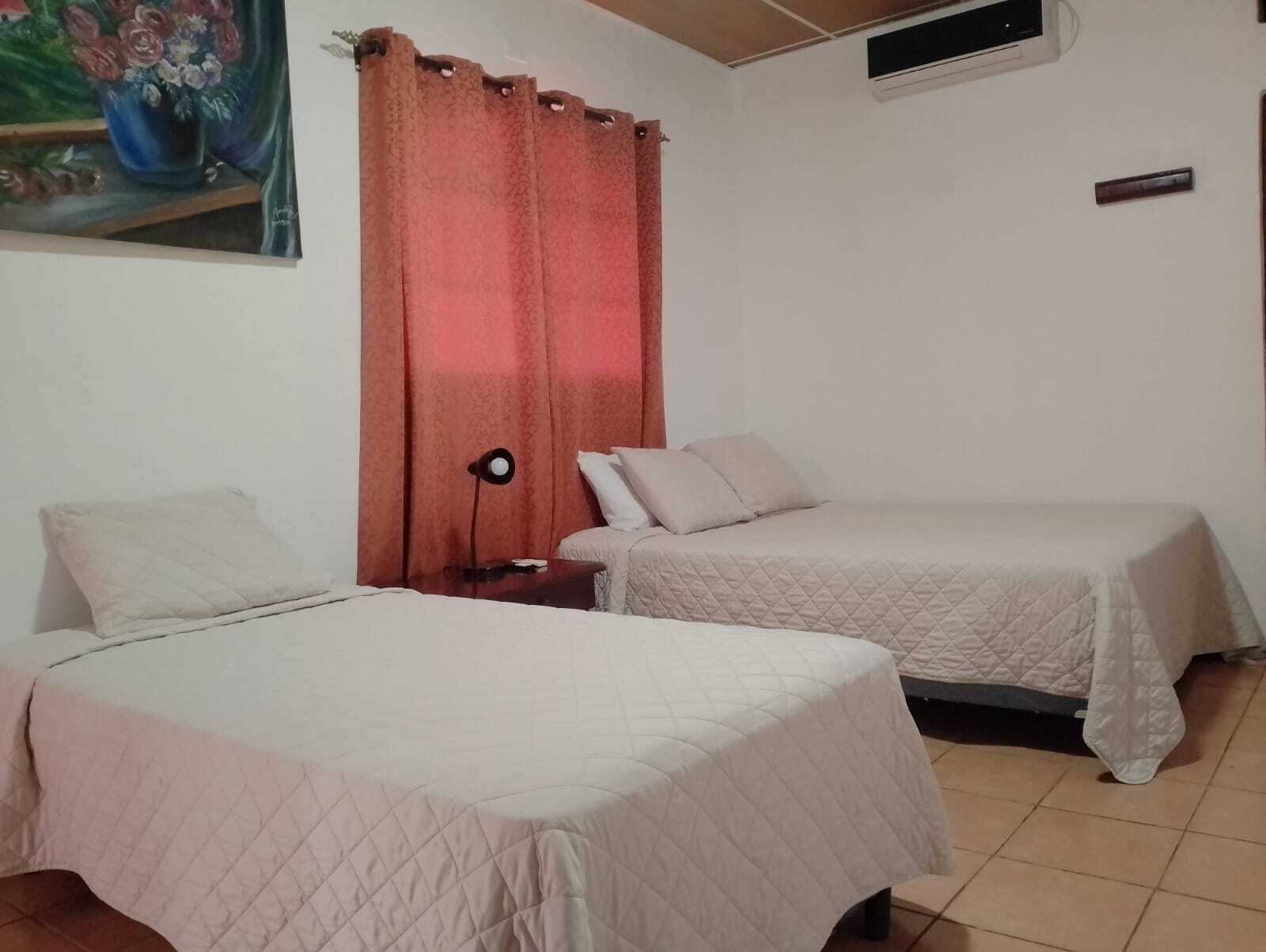 A room with two beds, a nightstand, a lamp, and a painting on the wall.