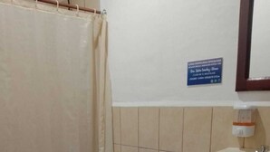 Un baño con inodoro, lavamanos, cubo de basura y cortina de ducha.