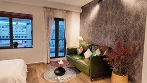 A modern hotel room with a green leather sofa, a round coffee table, a large window with curtains, and a view of the cityscape. - 1 BR Nguyen Hue Walking St Bitexco (Ho Chi Minh City)