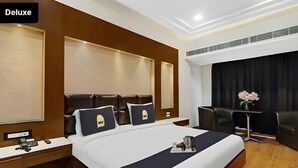 Una habitación de hotel de lujo con una cama grande, cabecera de madera, mesitas de noche, un escritorio y una silla.