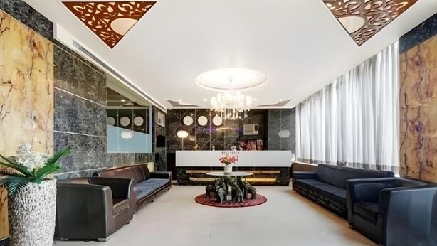 Un vestíbulo moderno con mostrador de recepción, zona de estar y paneles decorativos en el techo.