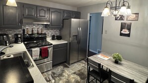 Une cuisine moderne avec des meubles de couleur sombre, des appareils électroménagers en acier inoxydable et un sol en marbre.