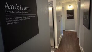 Un couloir avec une affiche murale définissant le terme « ambition » et un tableau encadré représentant le mot « succès ».