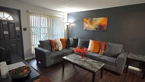 Un salon moderne avec un canapé gris, une table basse et un tableau accroché au mur.