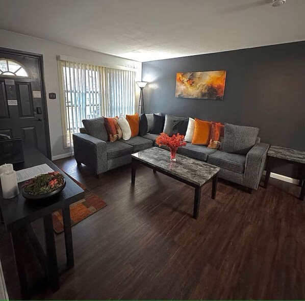 A modern living room with a grey sofa, a coffee table, and a painting on the wall.