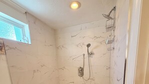 Ducha a pie con cabezal de ducha de mano y cabezal de ducha fijo en la pared.