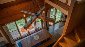 A wooden interior with a dining table, benches, and a staircase.