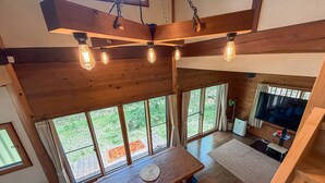 A spacious room with a large wooden table, multiple windows, and a television.