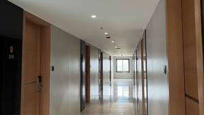 Een moderne hotelgang met houten deuren, een glanzende betegelde vloer en inbouwspots.