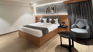 Een moderne hotelkamer met een groot bed, een nachtkastje met een lamp, een stoel en een tv aan de muur.