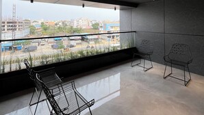 Een moderne kamer met een groot raam, een balkon en twee metalen stoelen.