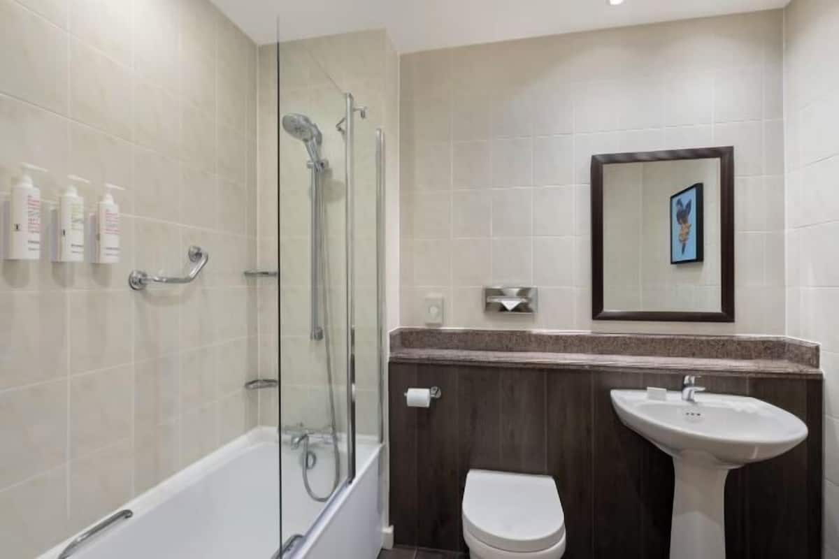 A modern bathroom with a glass-enclosed shower, a white toilet, and a pedestal sink.