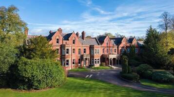 A large, multi-story brick building with a symmetrical facade, a central entrance, and a well-maintained lawn.