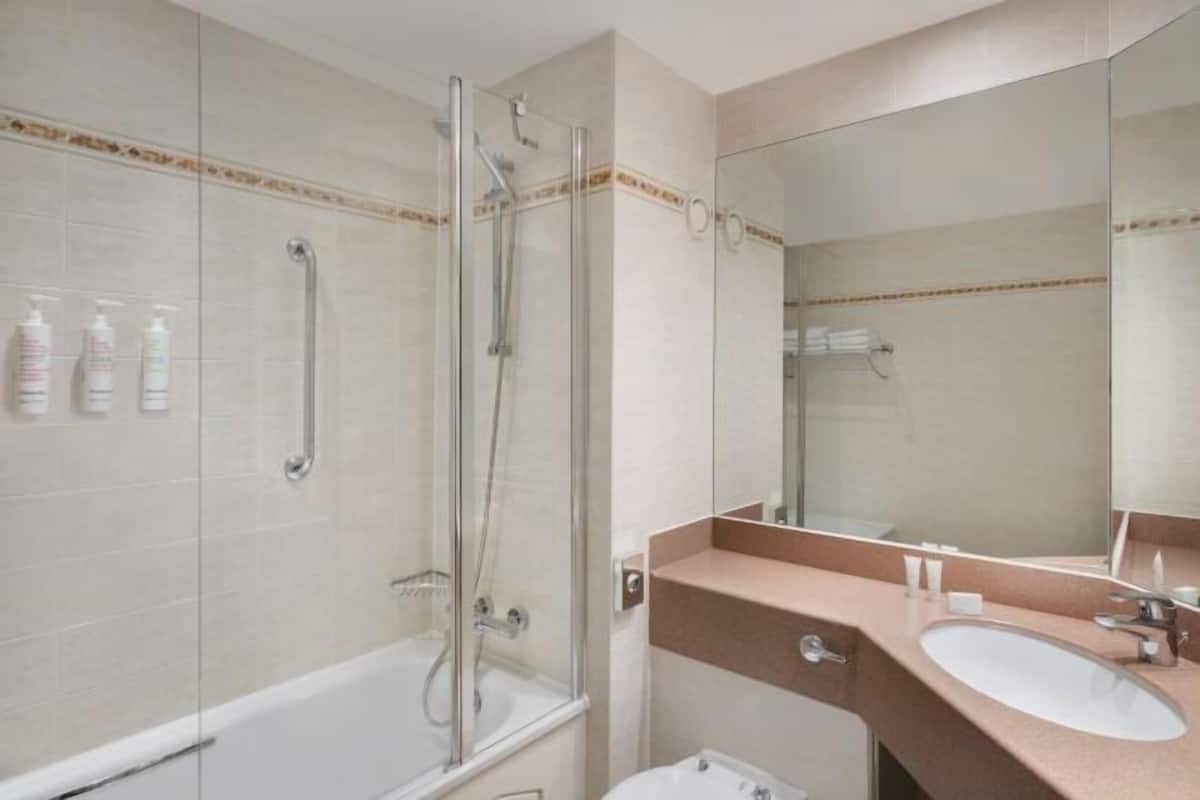 A bathroom with a glass-enclosed shower, a sink, and a mirror.