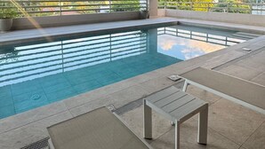 Ein moderner Poolbereich im Innenbereich mit freiem Blick auf umliegende Gebäude und Grünflächen.