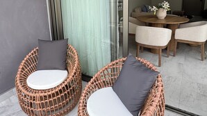 Ein modernes Interieur mit Korbstühlen, einem Essbereich und einem großen Spiegel, der den Raum widerspiegelt.