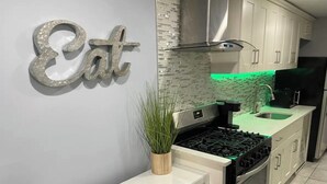 A modern kitchen with white cabinetry, a gas stove, and a stainless steel range hood.