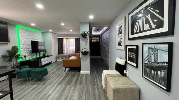 A modern living room with a sofa, ottoman, and a TV on a stand.