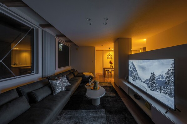 Ein modernes Wohnzimmer mit einer Couch, einem Couchtisch und einem Flachbildfernseher.
