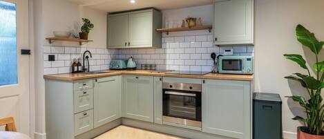 Una cocina moderna con armarios de colores claros, encimera de madera y horno empotrado.