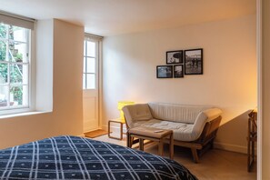 Ein Schlafzimmer mit einem Bett, einem Sessel, einer Couch und einem Fenster.