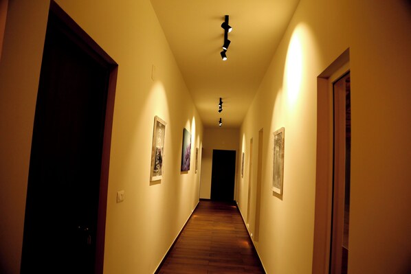 A hallway with wooden flooring and framed pictures on the walls.