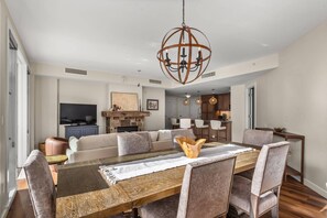 Ein modernes Wohnzimmer mit einem Holzesstisch, gepolsterten Sitzmöglichkeiten und einem zentralen Kronleuchter.