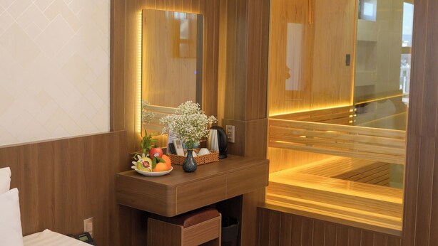 Une salle de bain moderne avec un meuble-lavabo en bois, un grand miroir et un sauna visible à travers la porte en verre.