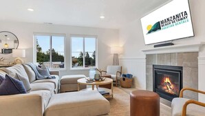 En moderne stue med pejs, komfortable siddepladser og et fjernsyn, der viser 'Manzanita Beach Getaway Vacation Rentals'.