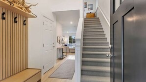 Et moderne interiør med trappe, en træbænk og en hvid dør.