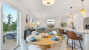 Et moderne køkken med en central ø, et spiseområde med et rundt bord og en opholdsstue med en sofa.
