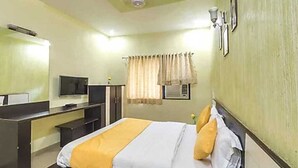 A hotel room with a bed, a desk, a television, and a window with curtains. - Hotel Star (Mohanpur)